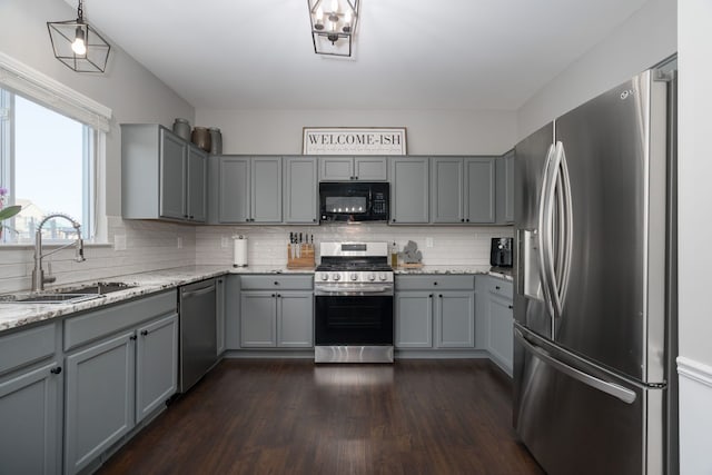 kitchen featuring stainless steel appliances, backsplash, a sink, and gray cabinetry