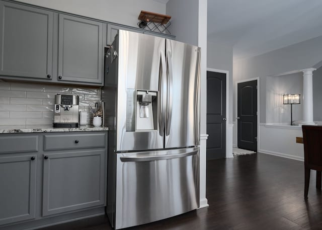 kitchen featuring dark wood-style flooring, backsplash, gray cabinetry, light stone countertops, and stainless steel fridge