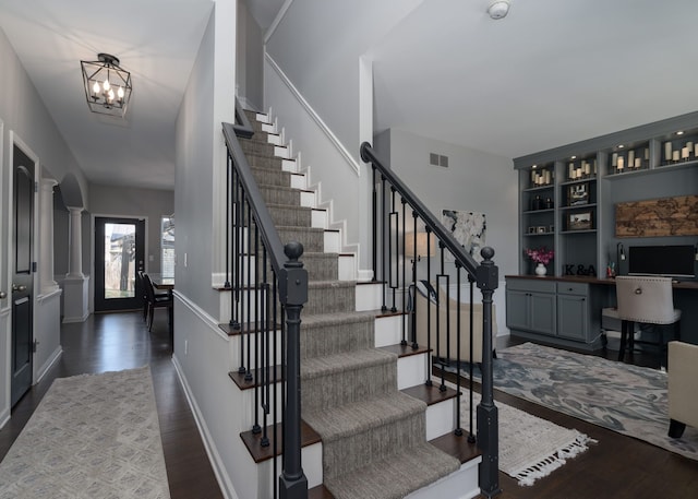 foyer with dark wood-style floors, decorative columns, visible vents, a chandelier, and baseboards