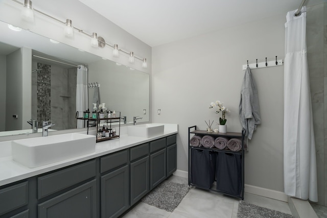 bathroom with baseboards, a sink, a shower with shower curtain, and double vanity