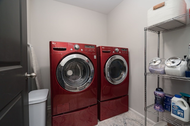 clothes washing area with baseboards, laundry area, and washer and dryer