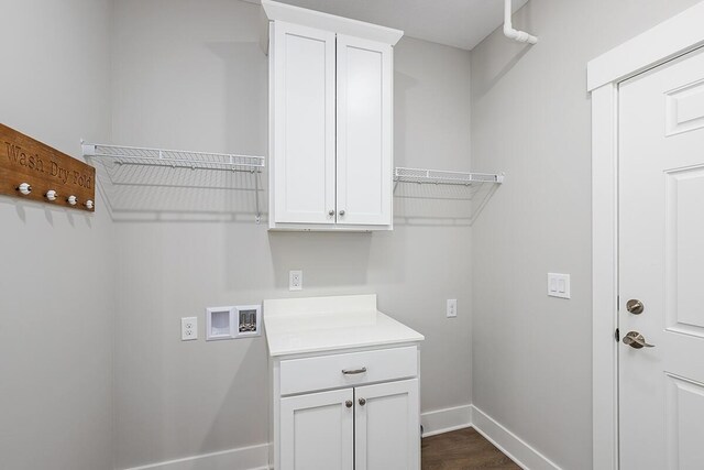 laundry area with hookup for a washing machine, cabinet space, baseboards, and dark wood-style floors