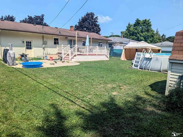 view of yard featuring a deck, an outdoor pool, and a patio