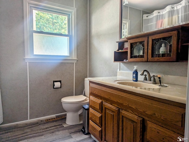 bathroom featuring toilet, wood finished floors, vanity, and baseboards