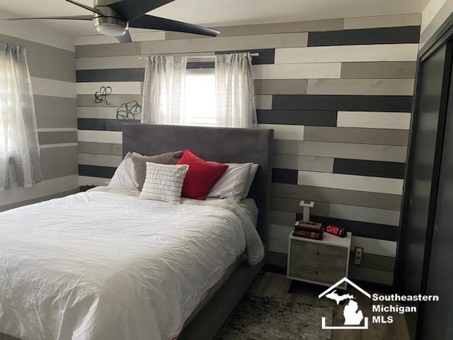 bedroom featuring wooden walls and a ceiling fan