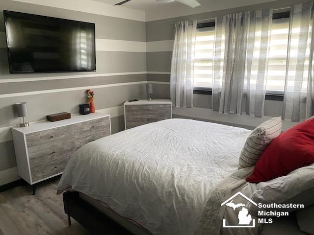 bedroom featuring multiple windows, ceiling fan, and wood finished floors