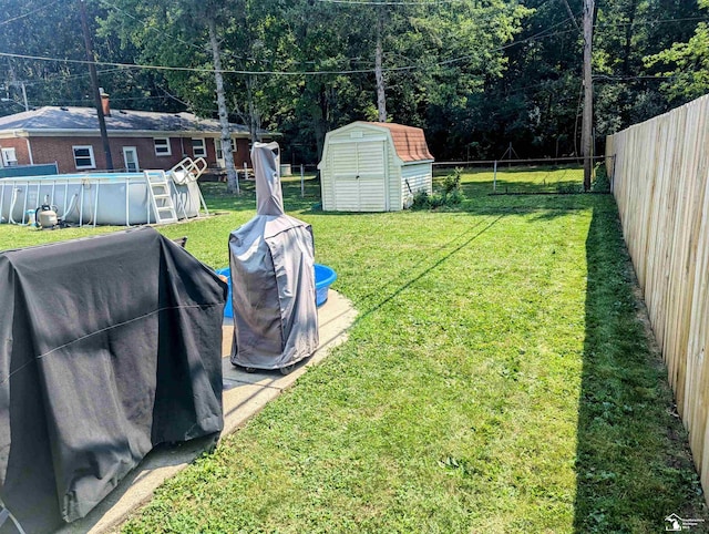 view of yard with an outbuilding, a fenced backyard, an outdoor pool, and a storage unit