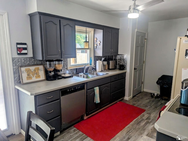 kitchen featuring tasteful backsplash, dark wood finished floors, light countertops, stainless steel dishwasher, and a sink