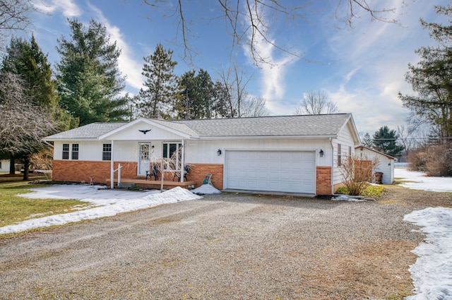 single story home with gravel driveway, brick siding, a porch, a shingled roof, and a garage