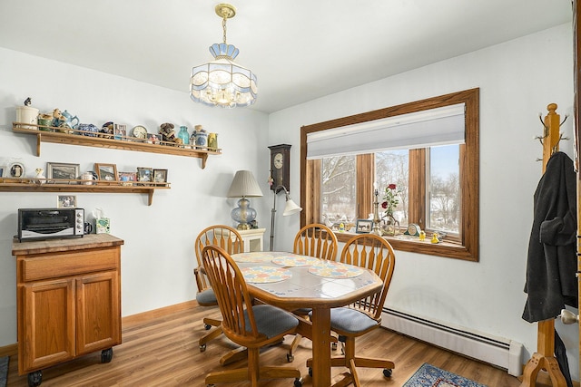 dining room with light wood finished floors, a baseboard radiator, a chandelier, and baseboards