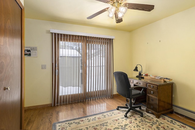 office featuring a baseboard heating unit, wood finished floors, a ceiling fan, and baseboards