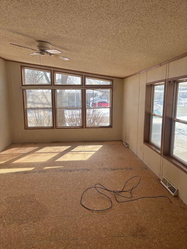 empty room with visible vents, ceiling fan, and a textured ceiling