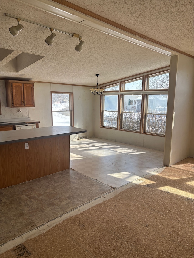 kitchen featuring brown cabinets, hanging light fixtures, and a textured ceiling