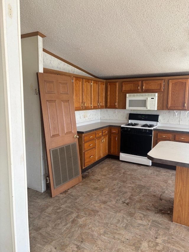 kitchen featuring lofted ceiling, white microwave, visible vents, range with gas stovetop, and brown cabinets