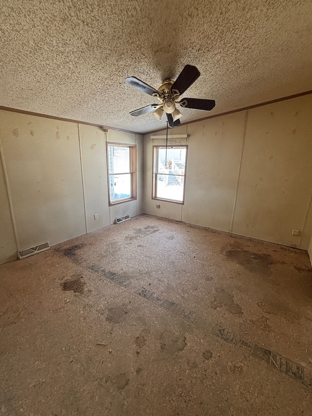 unfurnished room with a ceiling fan, visible vents, and a textured ceiling