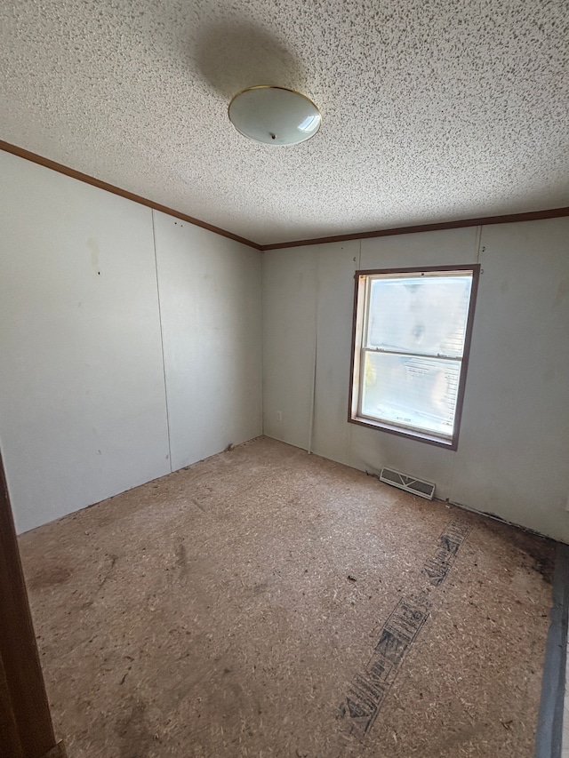 empty room with a textured ceiling, visible vents, and crown molding