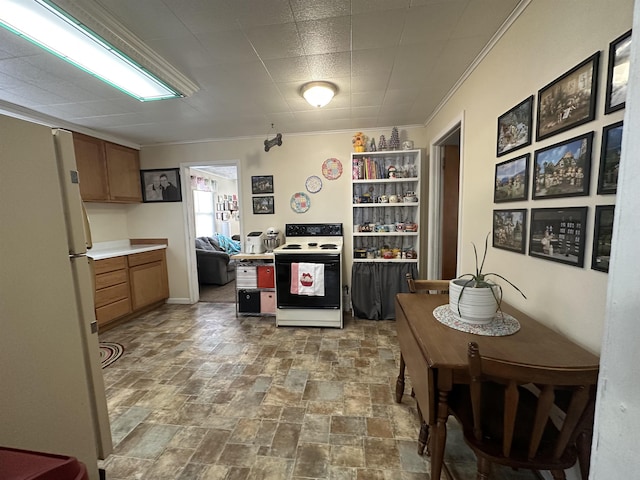 kitchen featuring range with electric cooktop, ornamental molding, stone finish flooring, freestanding refrigerator, and light countertops