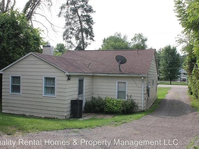 exterior space featuring a chimney and a shingled roof