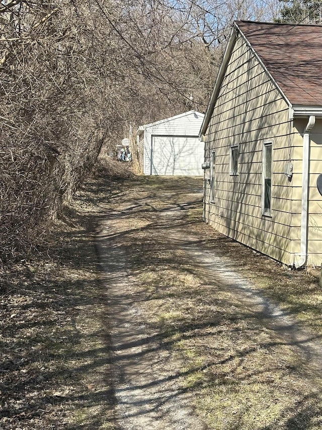 view of side of property featuring an outbuilding and roof with shingles