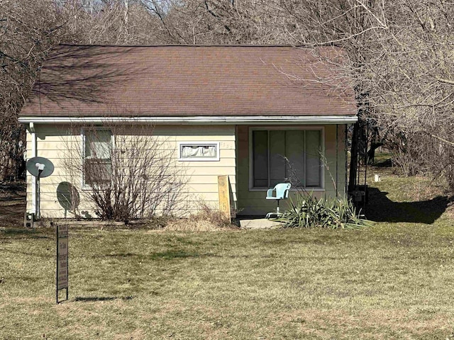 view of side of home with a lawn and a shingled roof