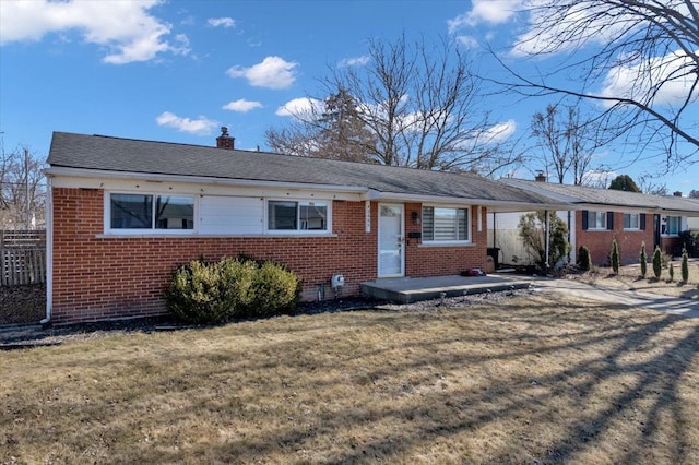 ranch-style home with an attached carport, fence, a chimney, a front lawn, and brick siding