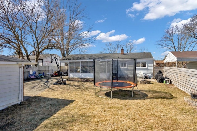 view of yard with a patio, a trampoline, a fenced backyard, and a sunroom