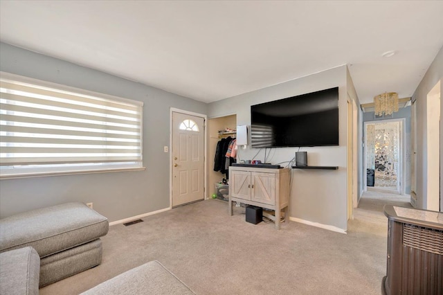 living area with baseboards, visible vents, a chandelier, and light carpet