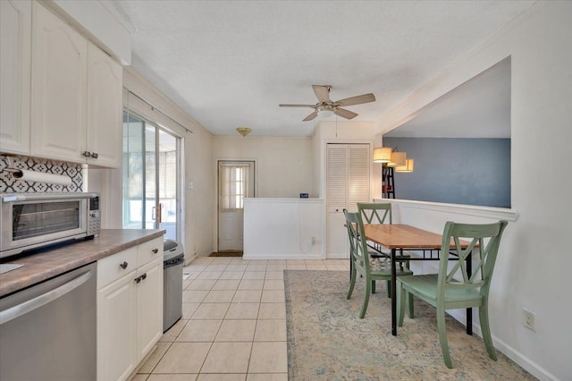 interior space with stainless steel dishwasher, light tile patterned flooring, white cabinetry, and ceiling fan