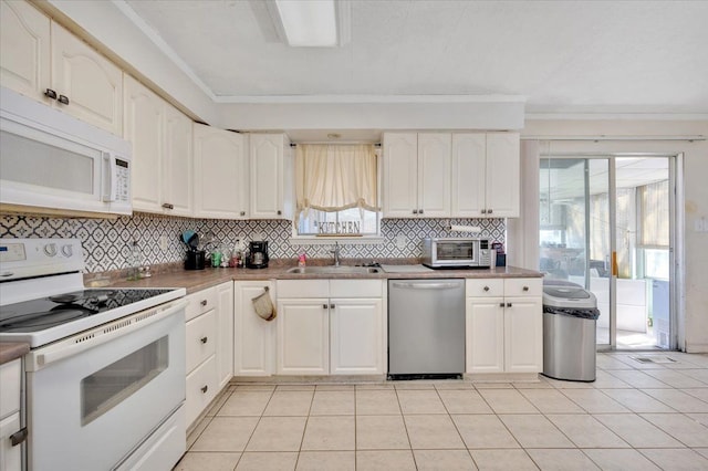 kitchen featuring white appliances, a sink, white cabinets, crown molding, and tasteful backsplash