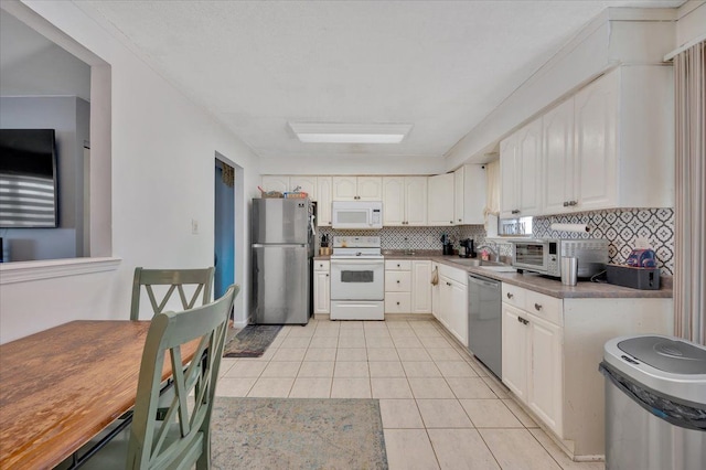 kitchen featuring backsplash, light tile patterned floors, appliances with stainless steel finishes, white cabinets, and a sink