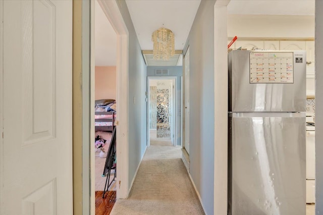 corridor featuring visible vents, baseboards, and light colored carpet