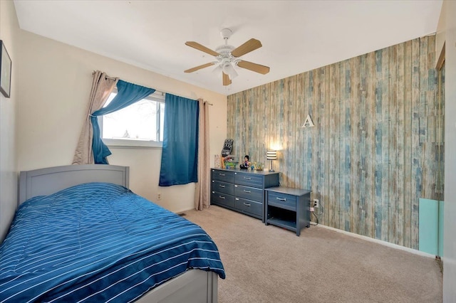 bedroom featuring baseboards, light carpet, an accent wall, and a ceiling fan