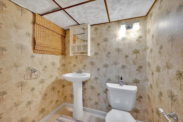 bathroom featuring tile patterned floors, baseboards, toilet, and a textured ceiling