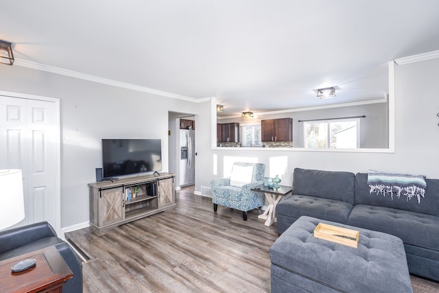 living area with visible vents, baseboards, wood finished floors, and crown molding