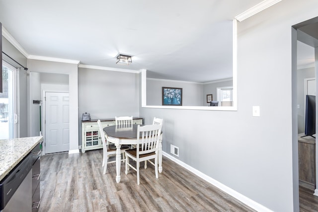 dining space featuring visible vents, baseboards, wood finished floors, and crown molding