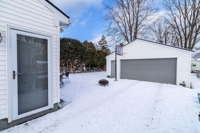 yard layered in snow featuring a garage and an outbuilding