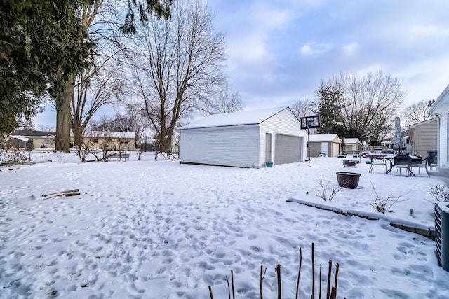 snowy yard featuring a garage and an outdoor structure