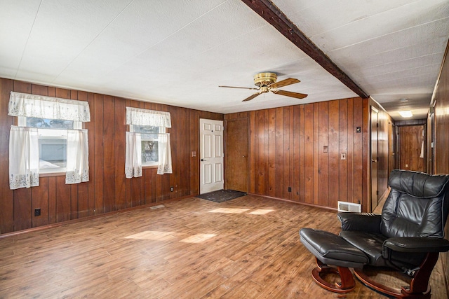 unfurnished room with baseboards, visible vents, a ceiling fan, wood finished floors, and beam ceiling