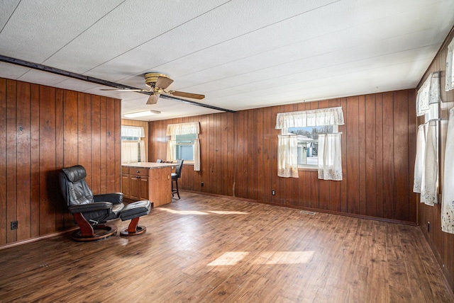 unfurnished room with a ceiling fan, wooden walls, baseboards, and wood finished floors