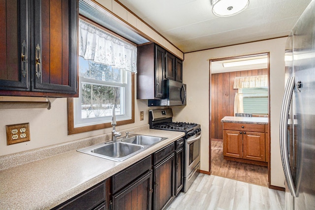 kitchen featuring light wood finished floors, light countertops, appliances with stainless steel finishes, and a sink