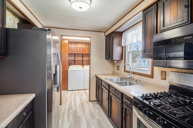 kitchen with a sink, appliances with stainless steel finishes, light countertops, and washer and dryer