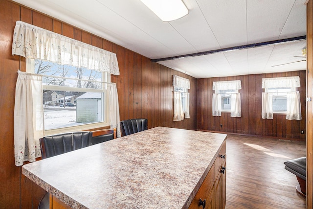 kitchen featuring dark wood-style floors, wooden walls, brown cabinets, and a center island