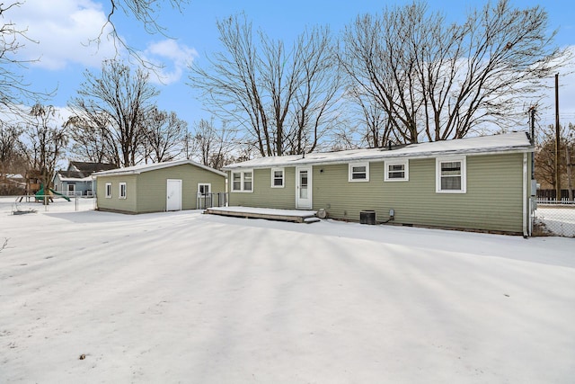 snow covered rear of property featuring a wooden deck, fence, central AC, and an outdoor structure