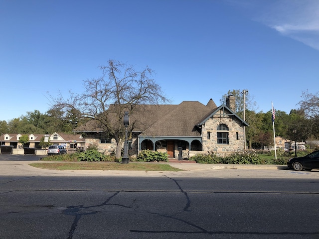 french country style house with stone siding and a chimney