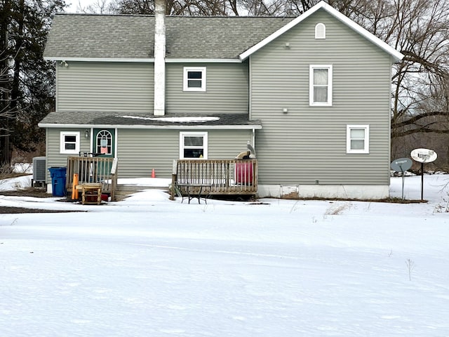 snow covered property featuring roof with shingles