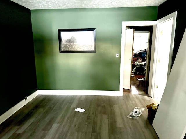 spare room featuring a textured ceiling, baseboards, and wood finished floors