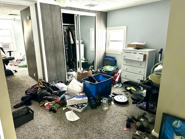 carpeted bedroom featuring cooling unit, a textured ceiling, visible vents, and a closet