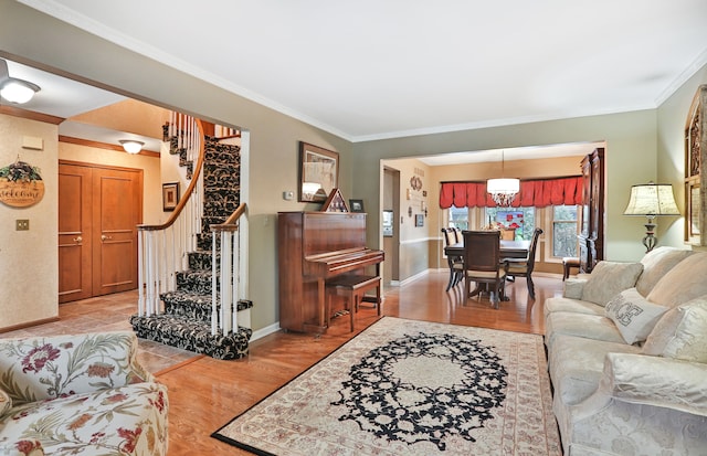 living area featuring light wood finished floors, ornamental molding, stairway, and baseboards