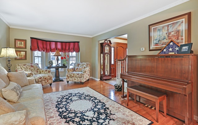 living area featuring ornamental molding, baseboards, and wood finished floors