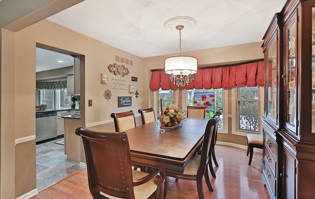 dining space with a wealth of natural light, visible vents, light wood-style flooring, and baseboards